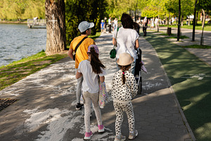 Family strolling by a river in a sunny park setting, a Person Photo by AS photostudio