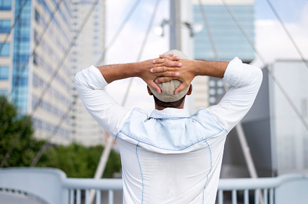Rear image of a man with his hands on his head looking towards the city., a Person Photo by RF Images