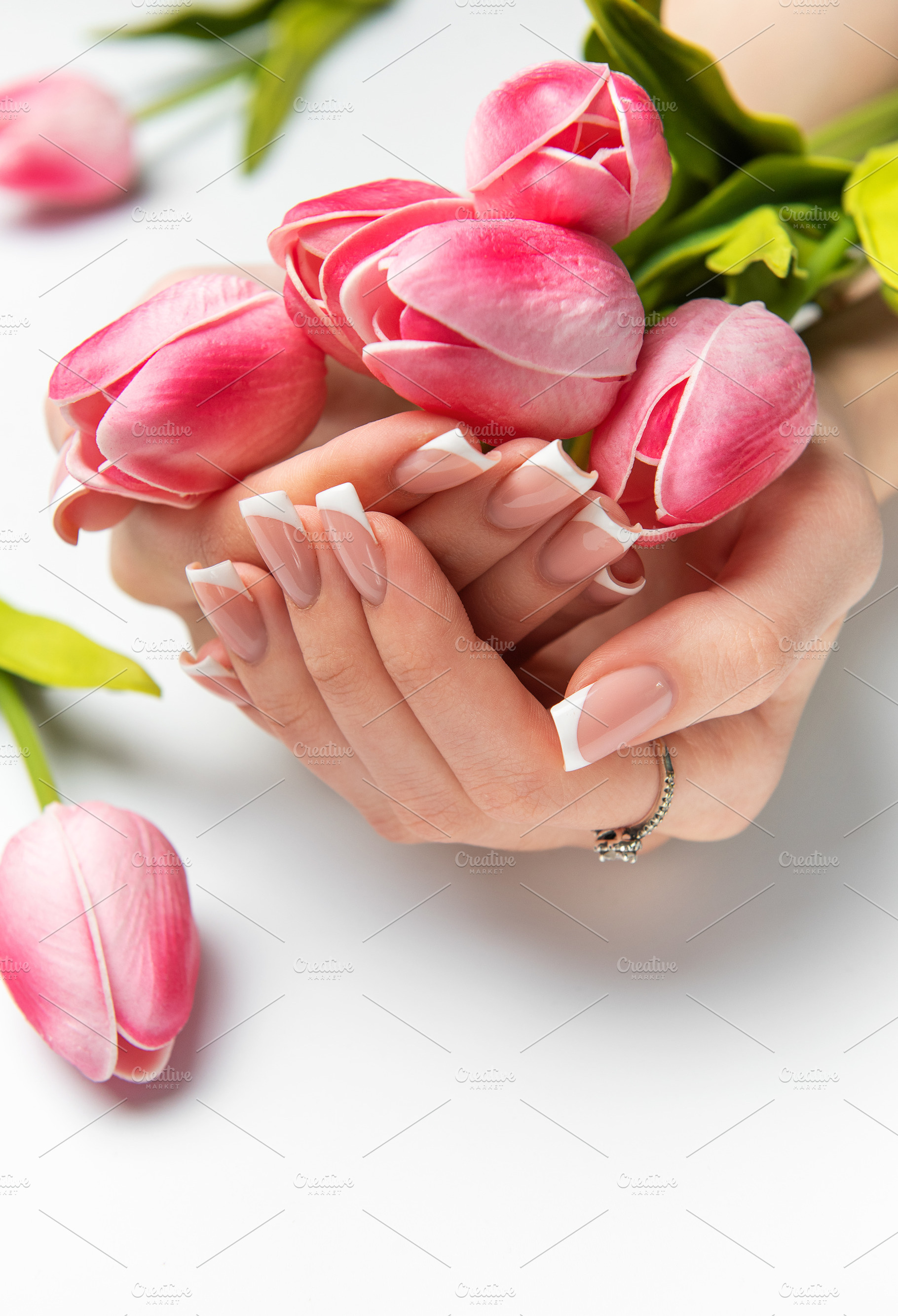 Woman holding pink tulips showing french manicure on white backg, a Beauty & Fashion Photo by Olena Rudo
