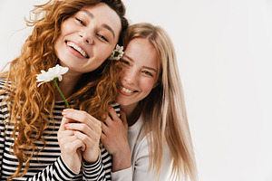 Young white two women hugging and smiling while posing with flowers