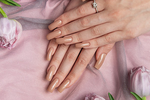 Woman showing nude manicure with engagement ring near pink tulip, a Beauty & Fashion Photo by Olena Rudo
