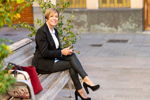 Businesswoman sitting on bench using smartphone, a Photo by RF Images