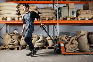 Male in apron pulling truck, an Industrial Photo by Artem Varnitsin