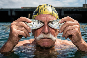 Elderly Man Holding Fish Over Eyes, a Person Photo by Virgo Studio