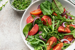 Fresh green salad with tomatoes and red onion, a Food & Drink Photo by Olena Rudo