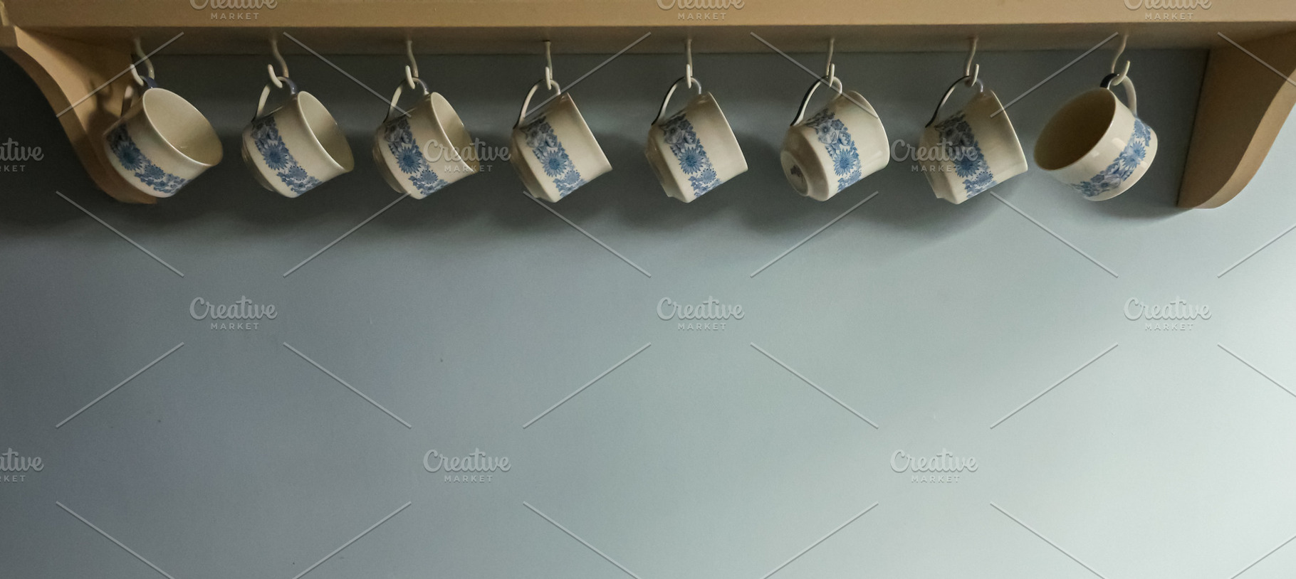 Row of hanging vintage cups with blue floral pattern on kitchen shelf. Cotswold, a Photo by Studio ANNA