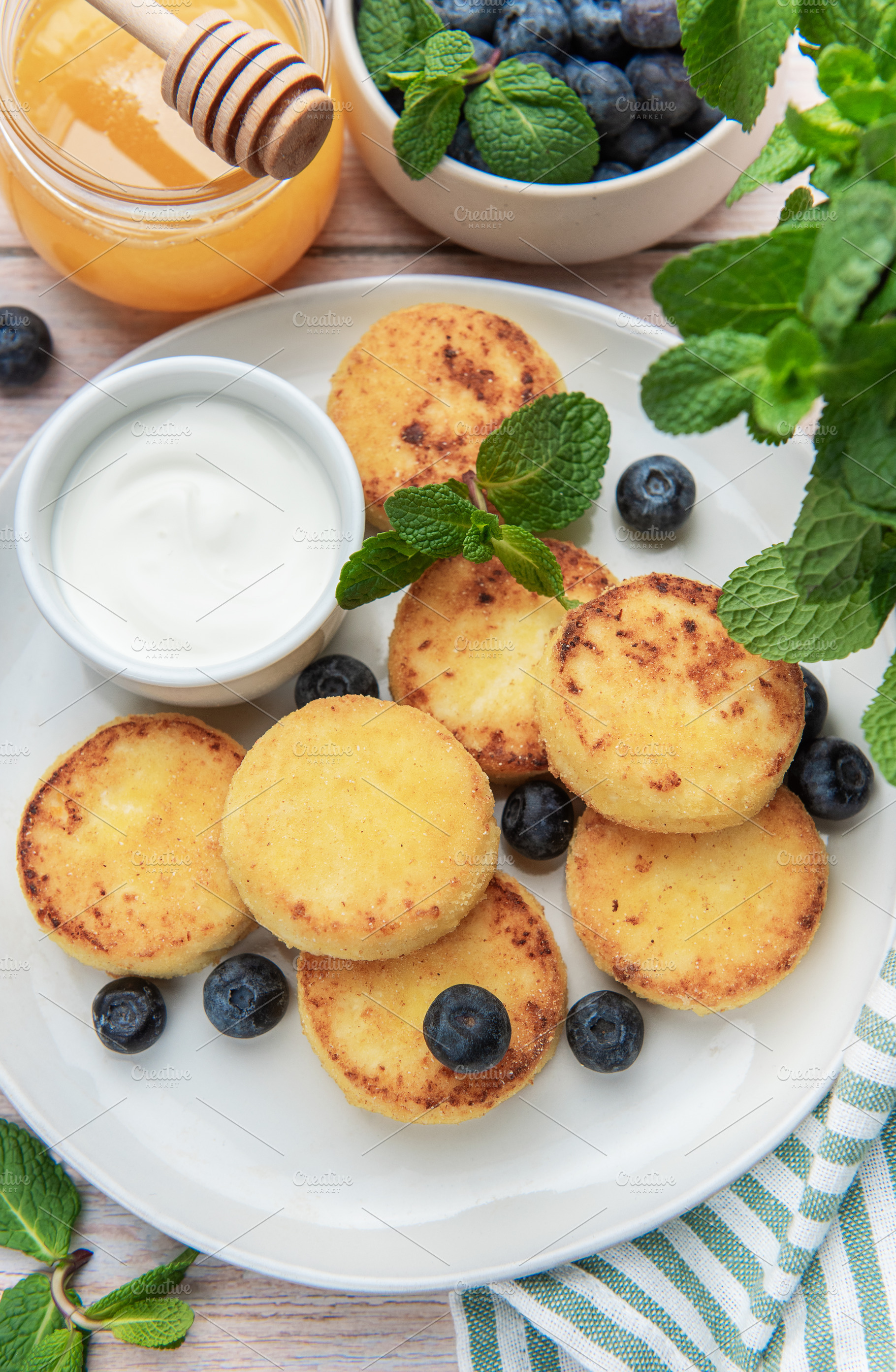 Syrniki pancakes with blueberries, sour cream, and honey, a Food & Drink Photo by Olena Rudo