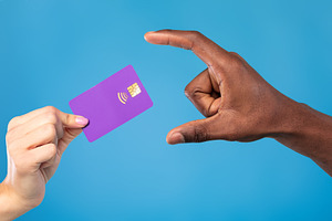 Closeup view of young woman giving credit card to African American man on blue, a Photo by Prostock-Studio