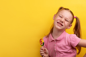 Cheerful young girl in pink shirt holding a colorful lollipop an, a Person Photo by Ales Munt