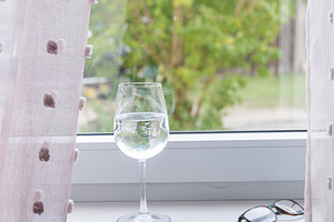 Empty wine glass on windowsill with soft daylight, an Industrial Photo by MDBildes