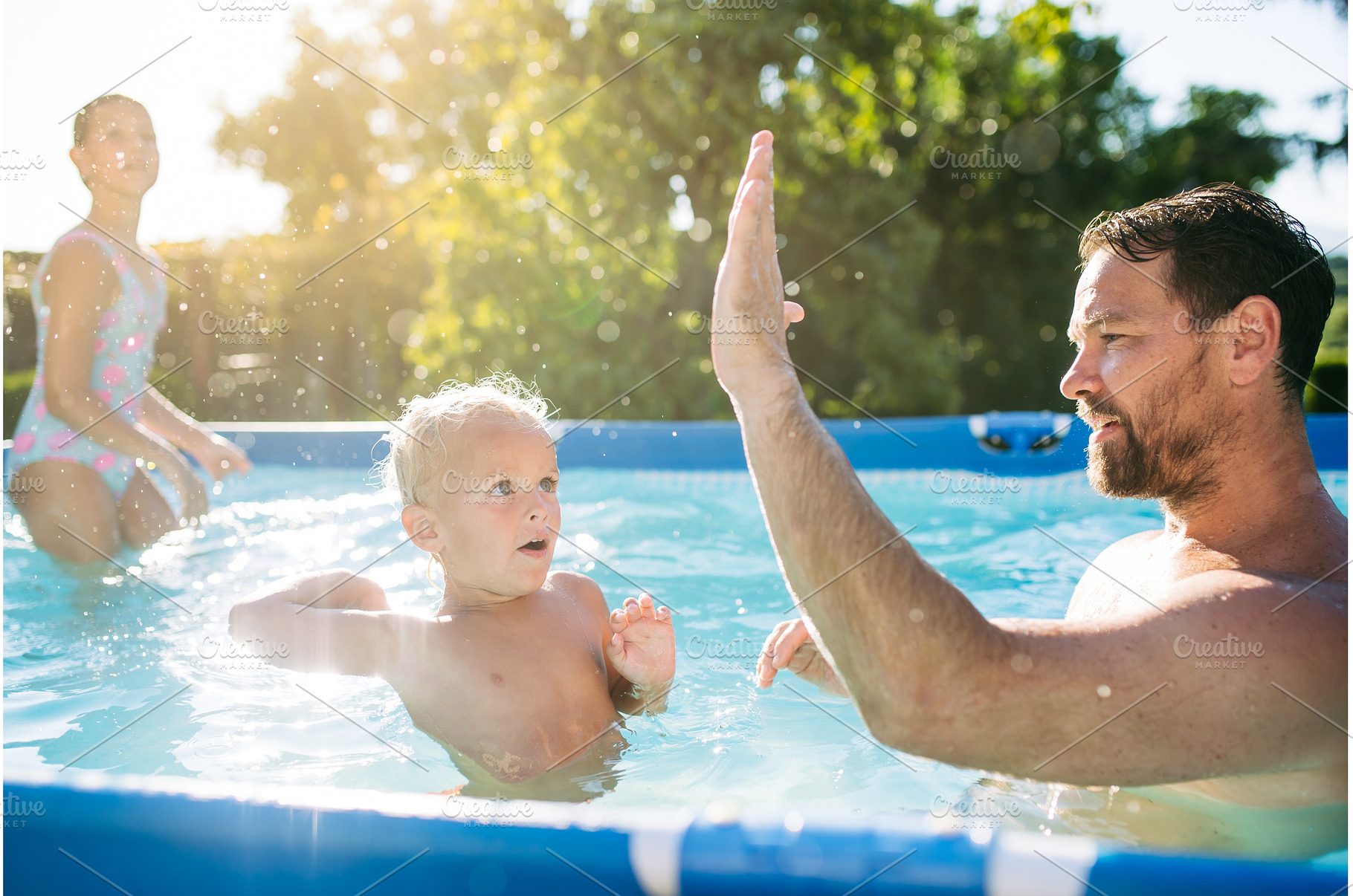 Father playing in swimming pool with, a Person Photo by HalfPoint
