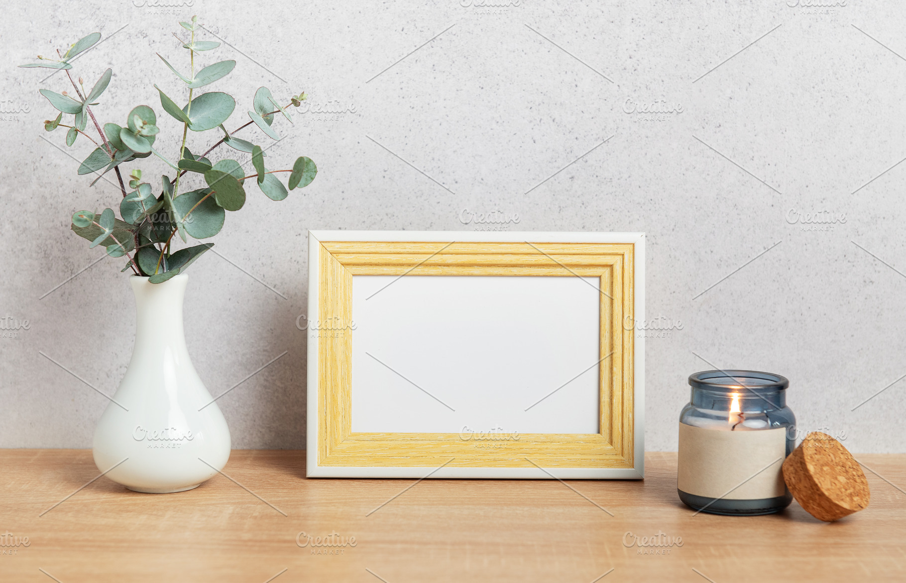 Empty photo frame, eucalyptus leaves and scented candle on woode, a Background Photo by Olena Rudo