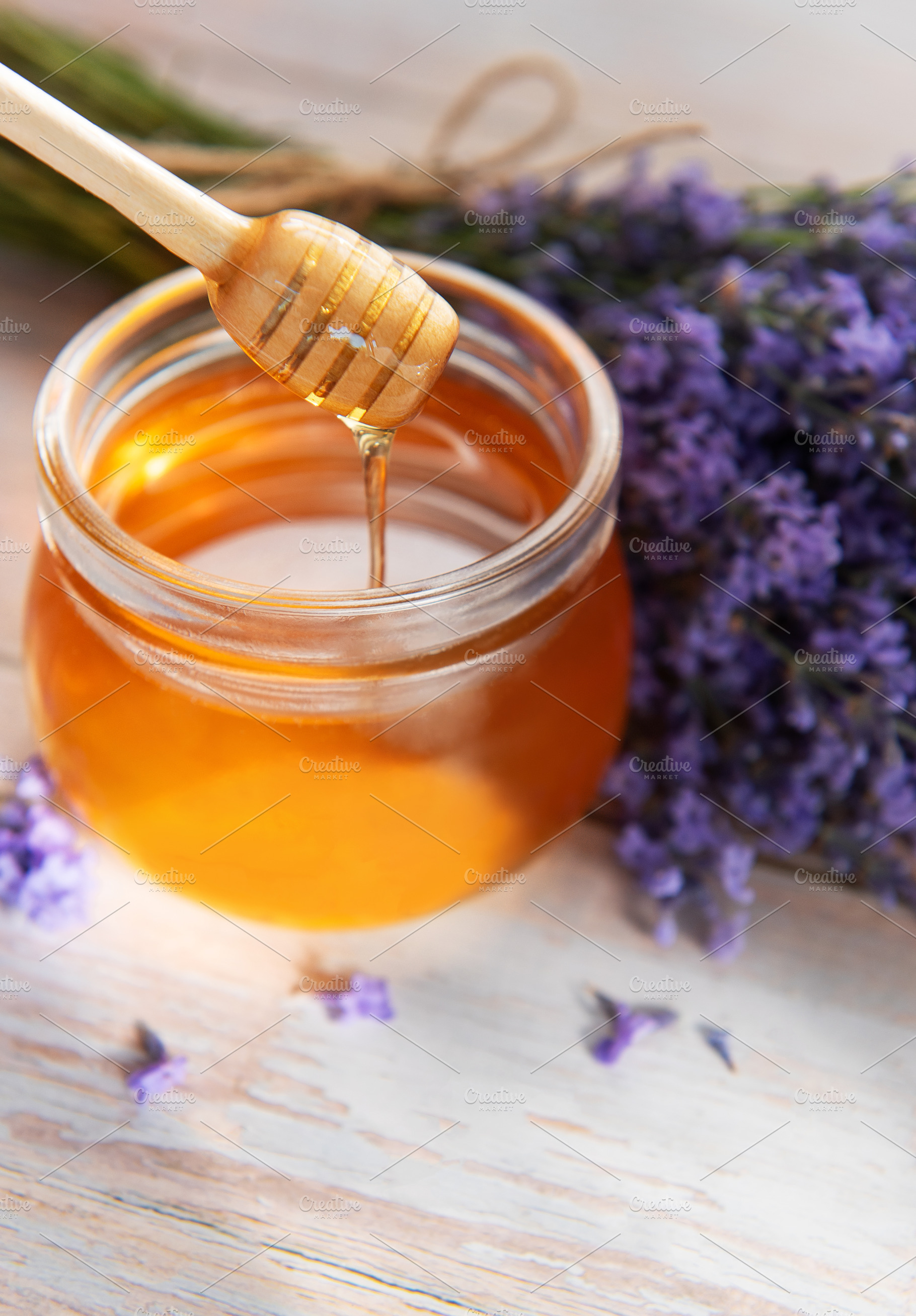 Golden honey dripping from dipper with lavender flowers, a Food & Drink Photo by Olena Rudo