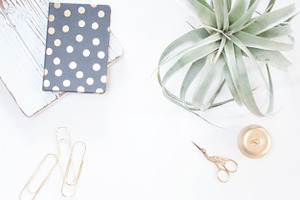 Minimalistic gold and white desk containing stock photo, gold paperclips, and