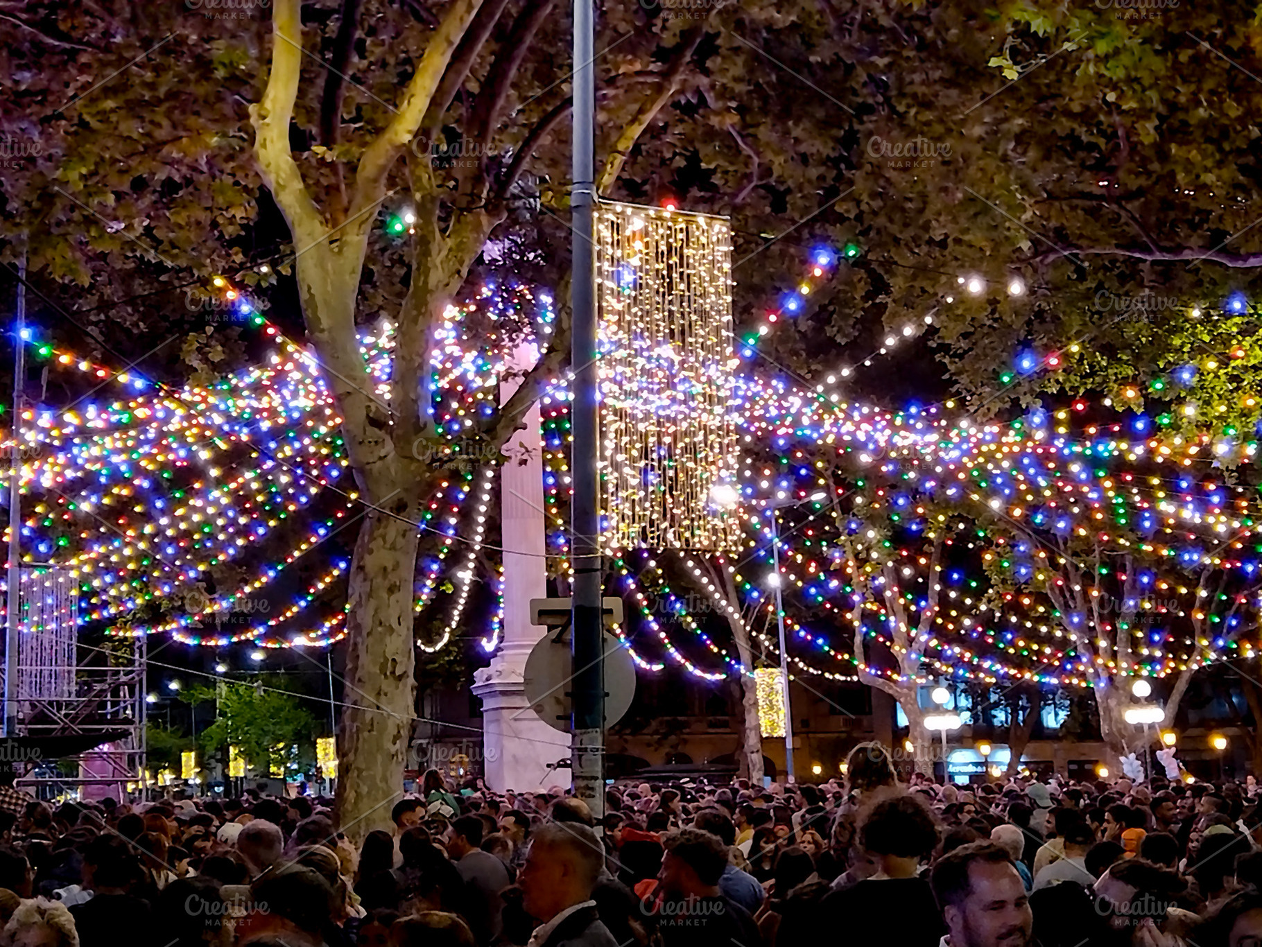 Crowd at a night festival with decorative lights, a Person Photo by DanFLCreativo