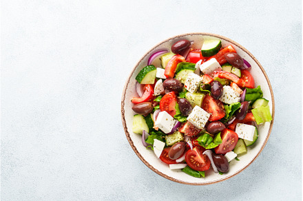 Greek salad in craft plate on white