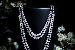 Elegant diamond necklace draping a black stand, sparkling on a d, a Photo by Studio ANNA