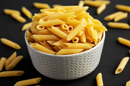 Organic Dry Penne Pasta in a Bowl on a black background, side vi, a Food & Drink Photo by LiudmylaChuhunova