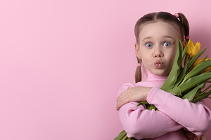 Cheerful young girl with pigtails hugs a bouquet of yellow tulip, a Holiday Photo by Ales Munt
