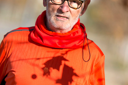 Senior man in red sportswear under autumn tree shadows