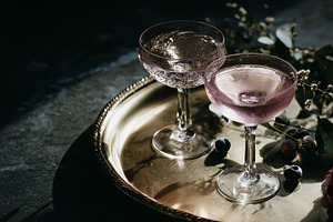 Sparkling pink cocktails on brass tray with fresh berries and eu, a Photo by Studio ANNA
