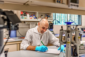 Smiling scientist writing in a labor, a Health & Medical Photo by Perpis