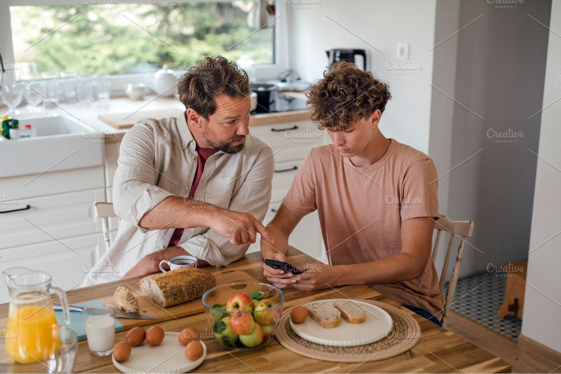 Father guiding teenage son using, a Technology Photo by HalfPoint