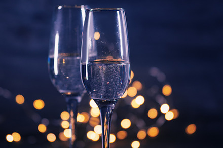 two glasses of champagne on a dark table with a garland of bokeh. Romantic even, a Holiday Photo by PavelKant