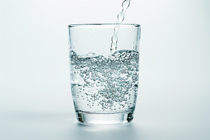 Pouring water into glass on white background, a Photo by AlyaAnd