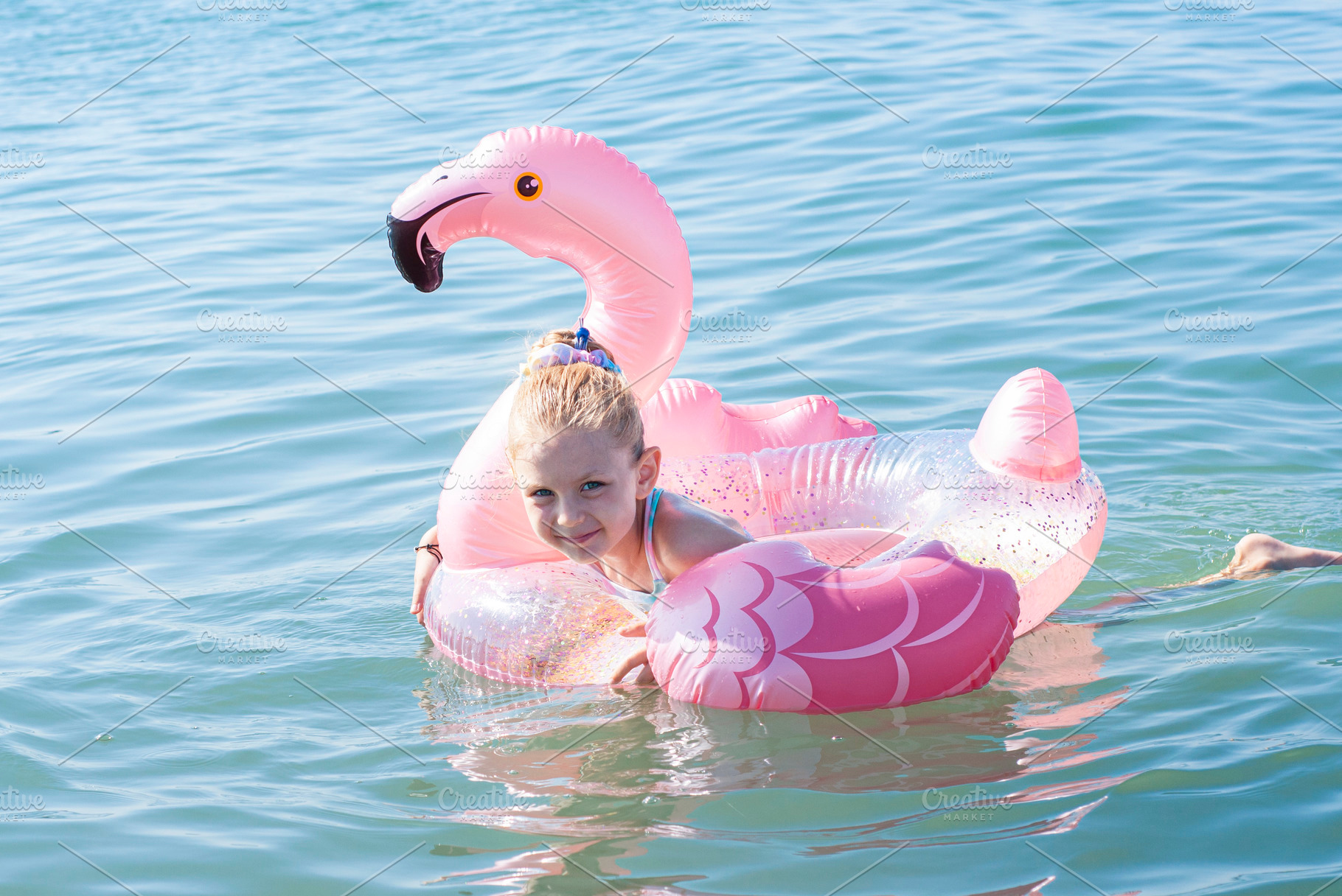 Little girl swims with a circle in the shape of a flamingo, a Person Photo by Olena Rudo