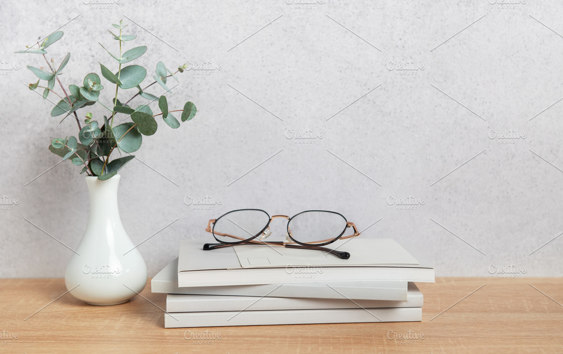 Eucalyptus branches, eyeglasses resting on books, and minimalist, a Background Photo by Olena Rudo