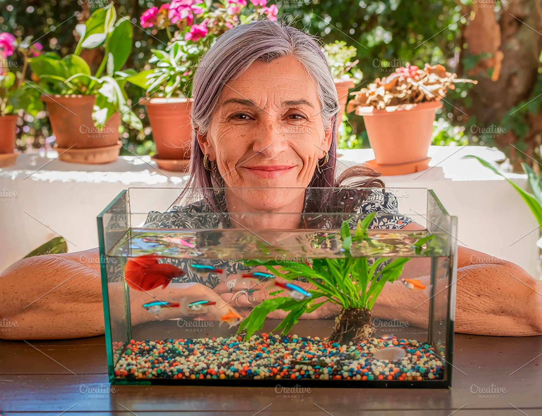 Mature woman posing with aquarium on a sunny balcony, a Person Photo by DanFLCreativo