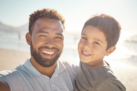 Happy, father and son smile in beach fun, vacation and break in summer happiness together. Portrait of dad and child selfie smiling in fun outdoor bonding free time on a sunny day at the ocean, a Photo by Peopleimages.com