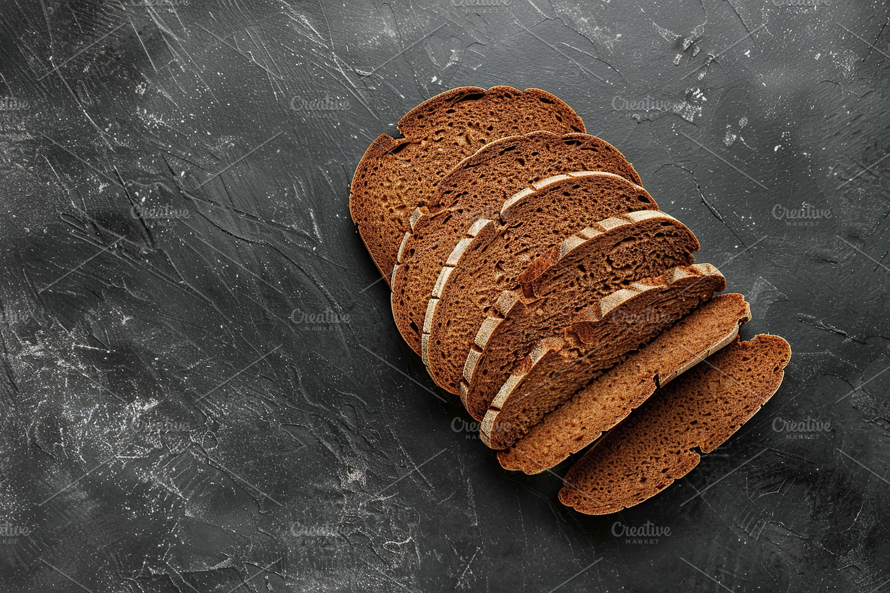 Sliced baked rye bread on black background, a Food & Drink Photo by AlyaAnd