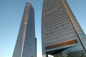 Tall skyscrapers with reflective glass under blue sky, an Architecture Photo by DanFLCreativo