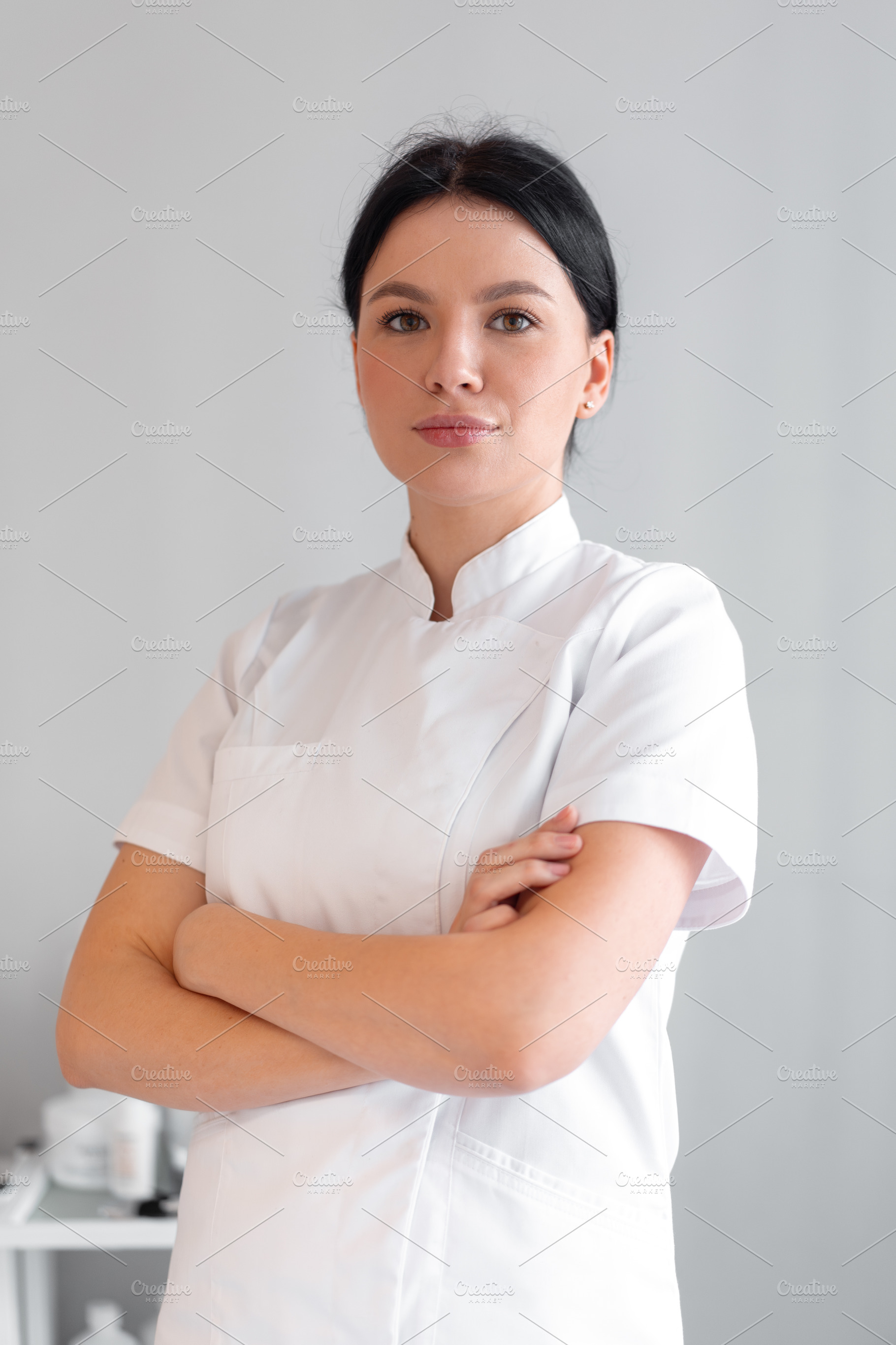Confident female cosmetologist in lab coat standing at clinic, a Photo by andreonegin market