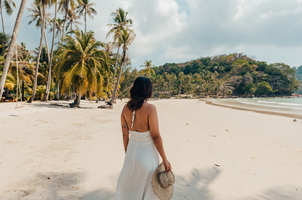 A woman in a hat enjoys the summer sun on a beautiful tropical b, a Holiday Photo by Art Rachen