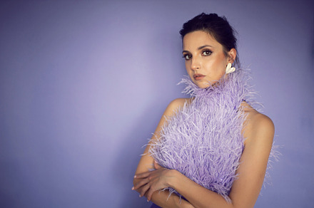 portrait woman in an evening purple dress with feathers stands in the backgroun, a Person Photo by SaulichPhoto