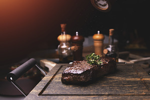 Chef adding salt and thyme to grilled steak, a Photo by Grafvision photography