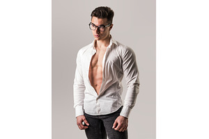 Young muscleman undressing in studio