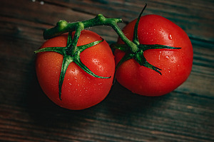 Fresh vine ripened tomatoes on rustic wooden surface with water drops represent, a Photo by Studio ANNA