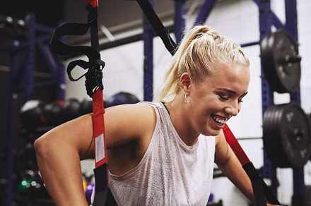Young woman laughing while working out at the gym