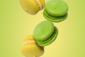 Levitating green and yellow macarons on a light green background, a Food & Drink Photo by ndanko