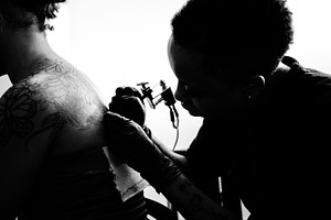 T a t t featuring tattoo, tattoo machine, and building