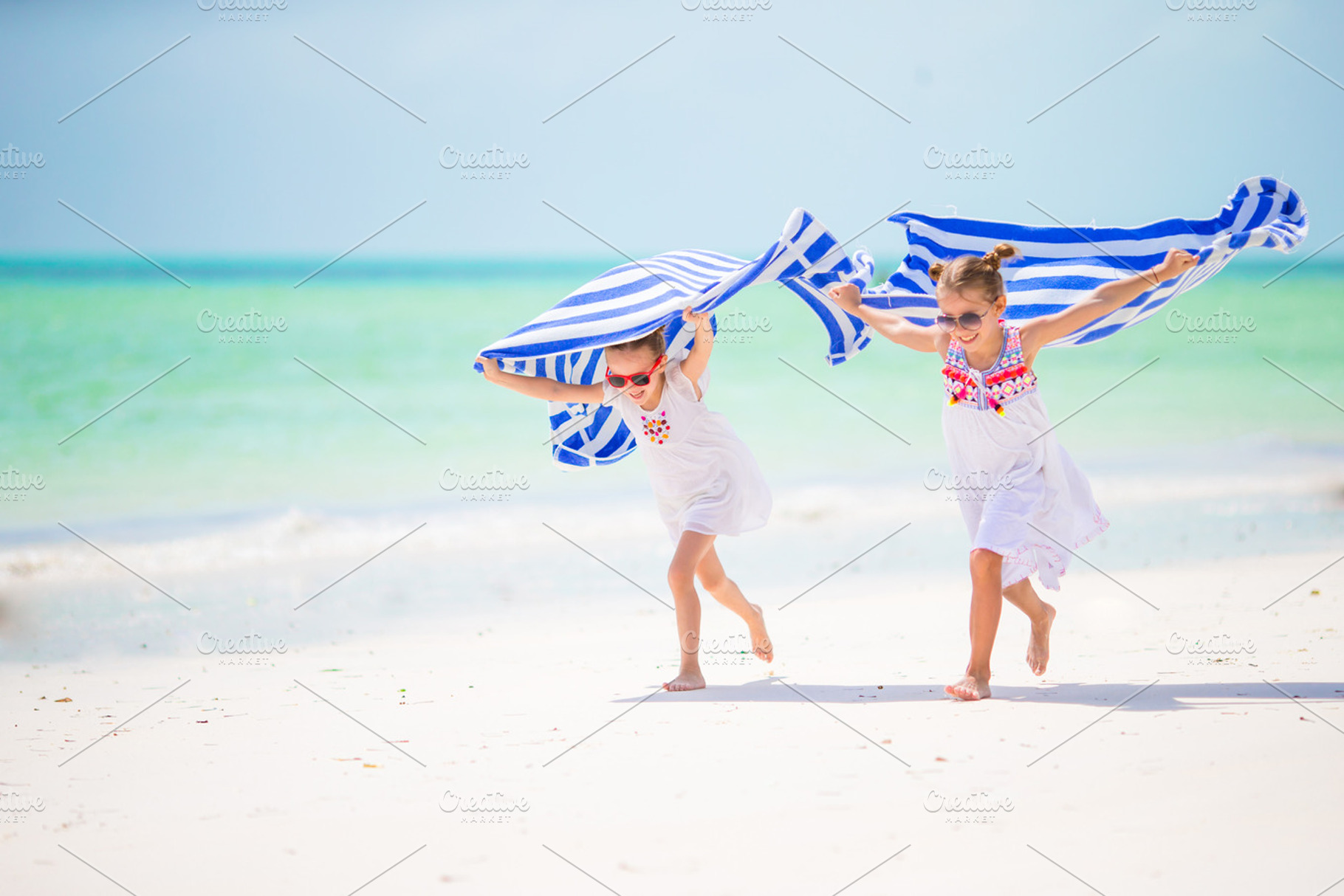 Little girls having fun running with towels on tropical beach containing, a Person Photo by travnikovstudio