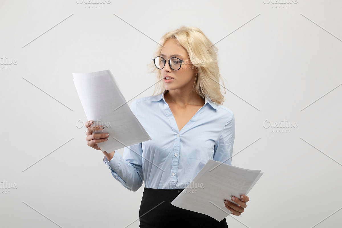 Serious businesswoman in formal wear and eyeglasses reading documents over ligh, a Photo by Prostock-Studio (Photo 2 of 2)