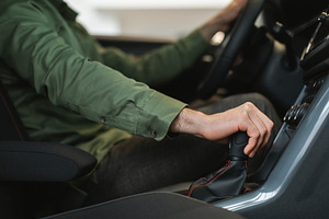 Unrecognizable young guy checking manual transmission in new car, going on test, a Photo by Prostock-Studio