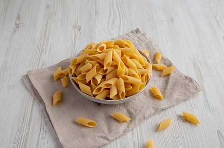 Raw Organic Dry Pennoni Pasta in a Bowl, side view., a Food & Drink Photo by LiudmylaChuhunova