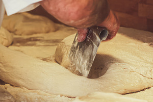 Baker dividing dough with metal scraper in bakery, an Abstract Photo by Antonio Gravante Market