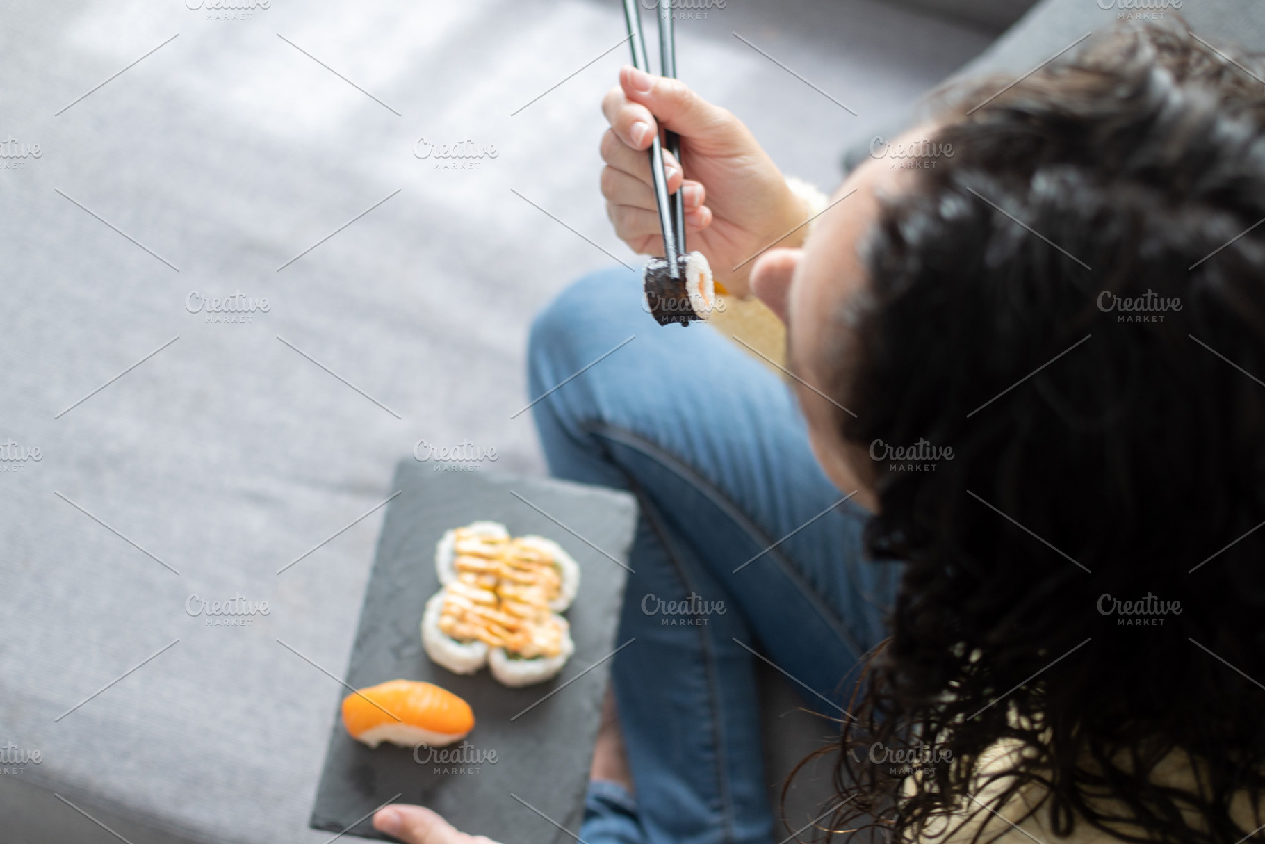 Woman Enjoying Sushi While Relaxing on Sofa at Home, a Person Photo by etorres69